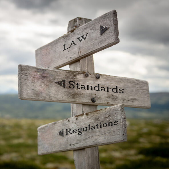 Signpost saying law standards and regulations, all pointing different directions